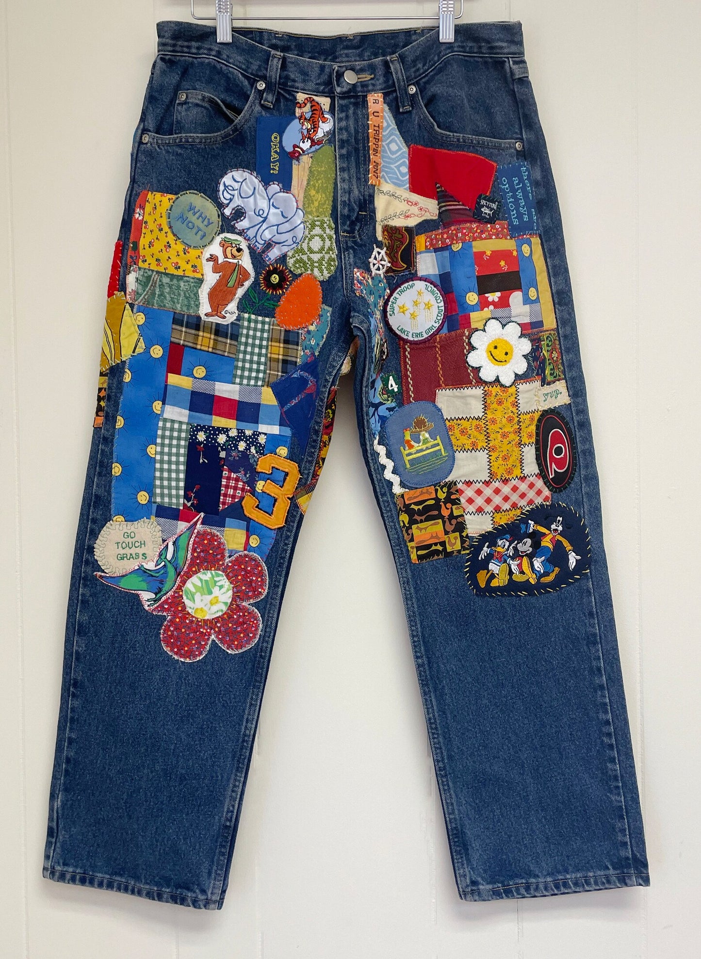 a pair of jeans with patches on them hanging on a wall