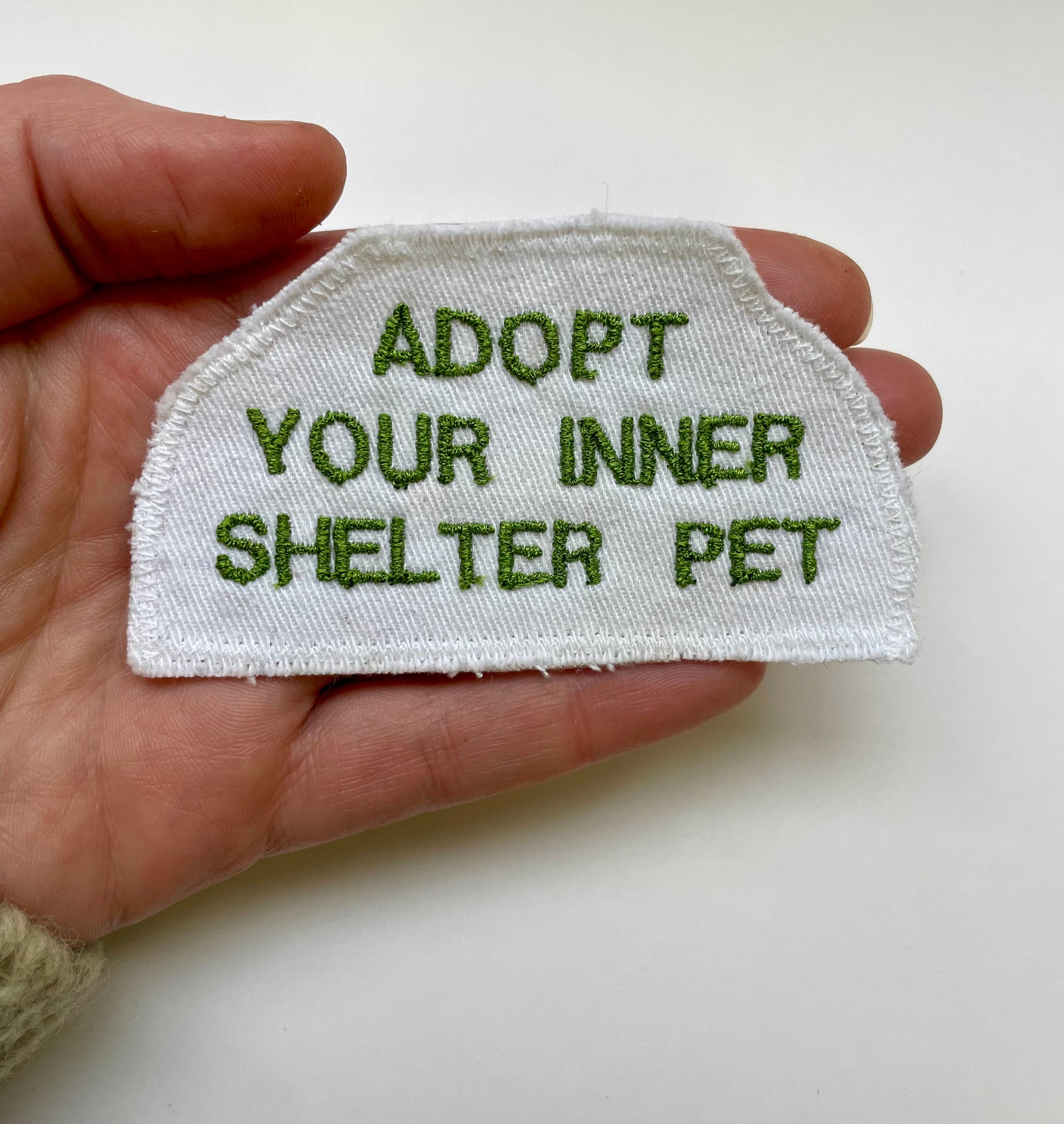 a hand holding a patch that says adopt your inner shelter pet