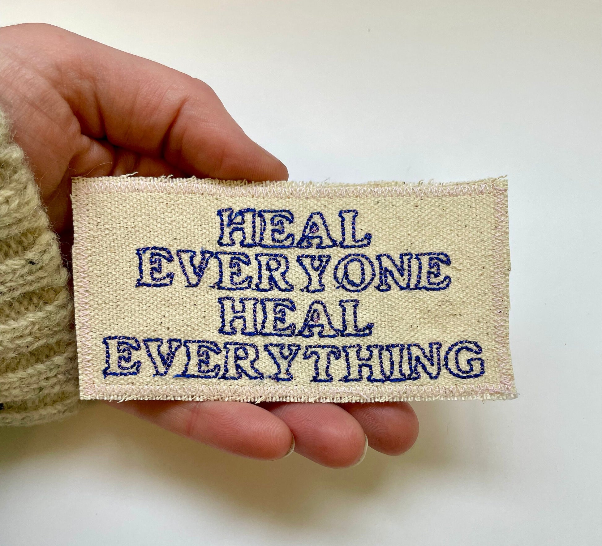 a hand holding a patch that says heal everyone heal everything