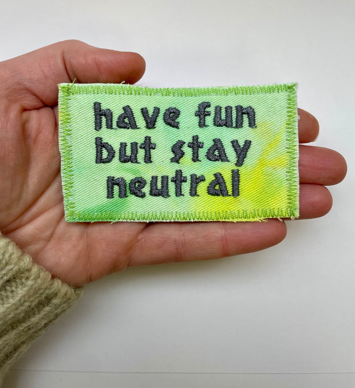 a hand holding a piece of cloth that says have fun but stay neutral