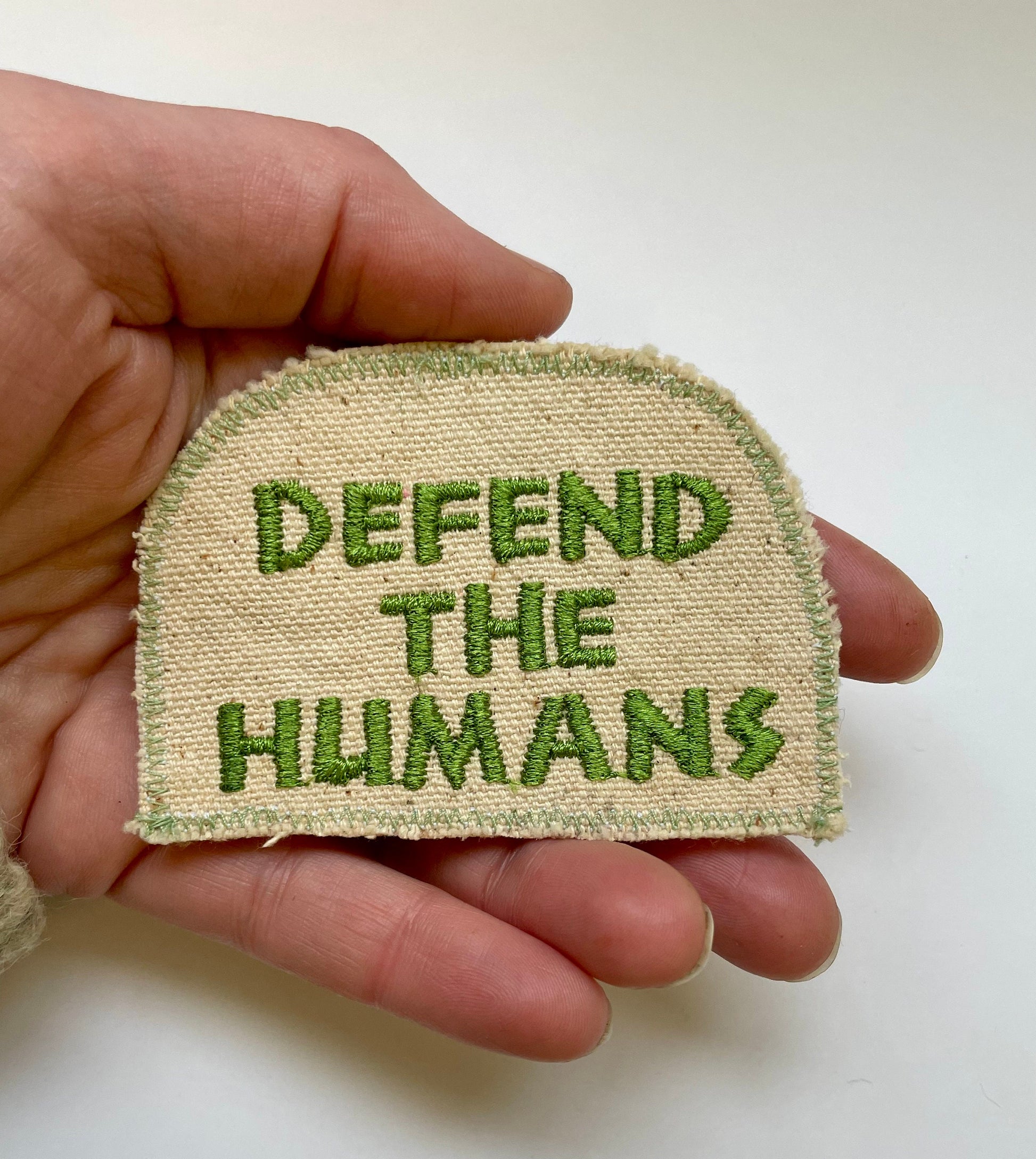 a hand holding a piece of cloth with the words defend the humans on it