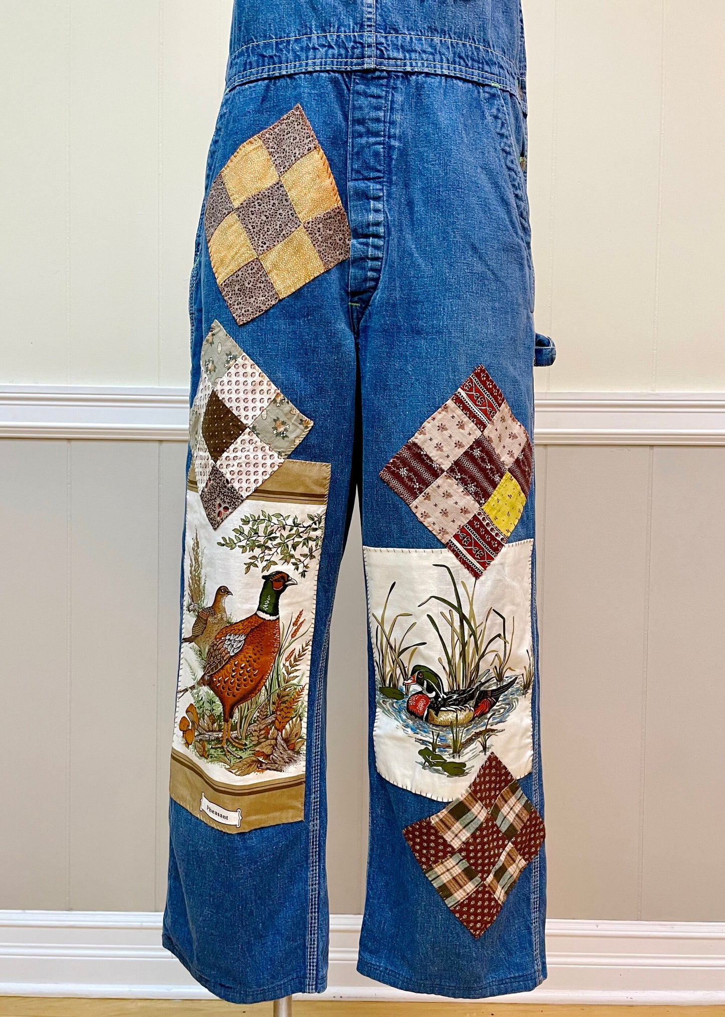 a pair of jeans with patchwork and a bird on them