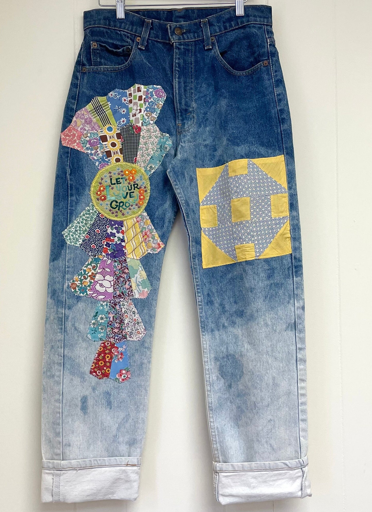 a pair of jeans with patches on them hanging on a wall